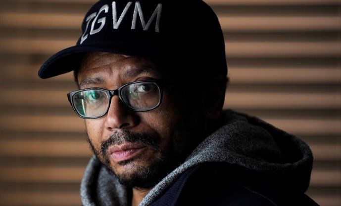 A man wearing a hat and glasses is looking at the camera.