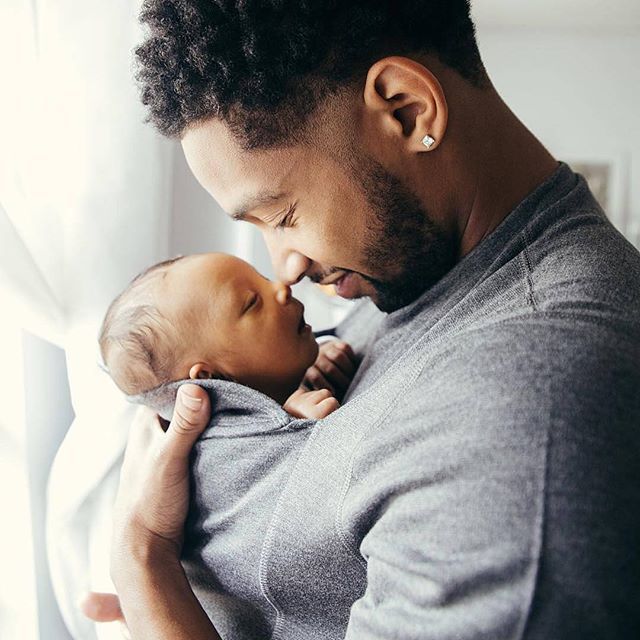 A man is holding a newborn baby in his arms.