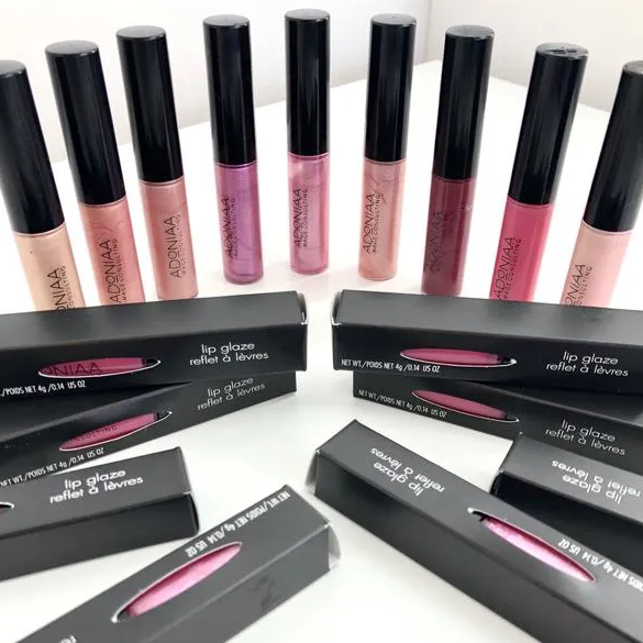 A variety of lip glosses are lined up on a table