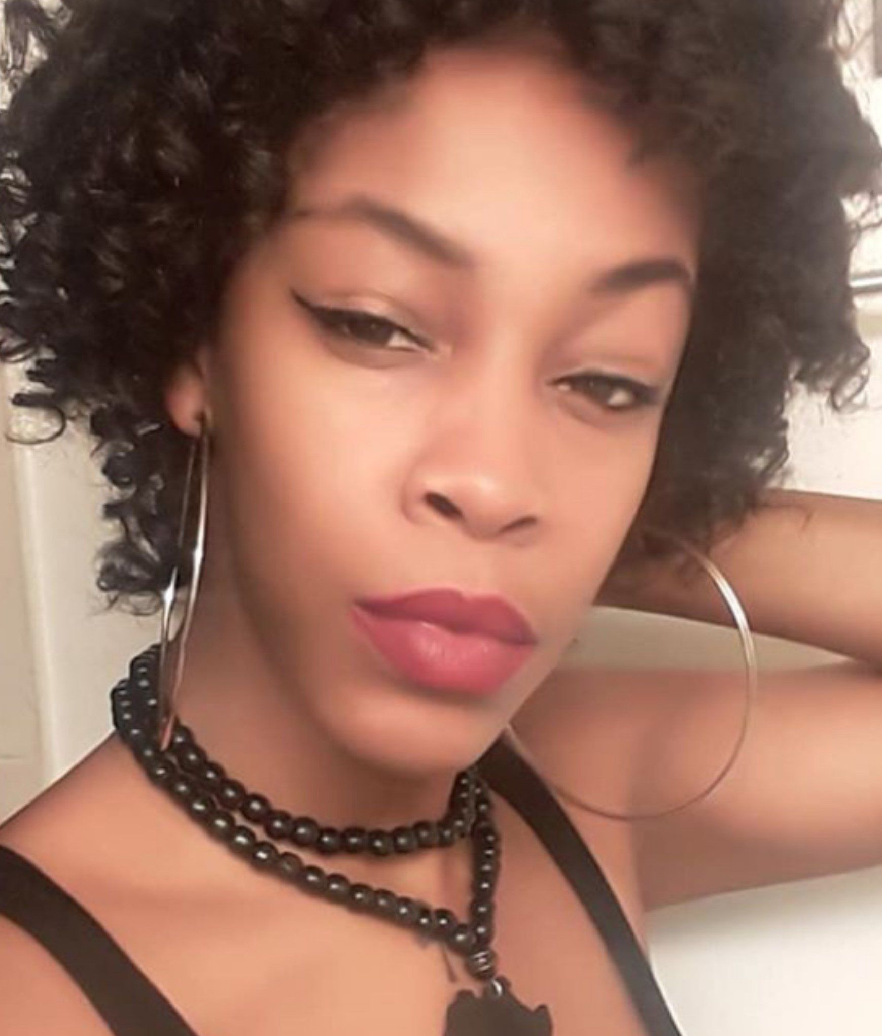 A woman wearing a choker necklace and hoop earrings