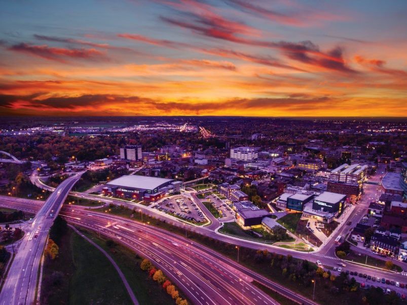 An aerial view of a city at sunset with a highway in the foreground.