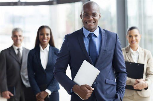 A man in a suit and tie is standing in front of a group of business people.