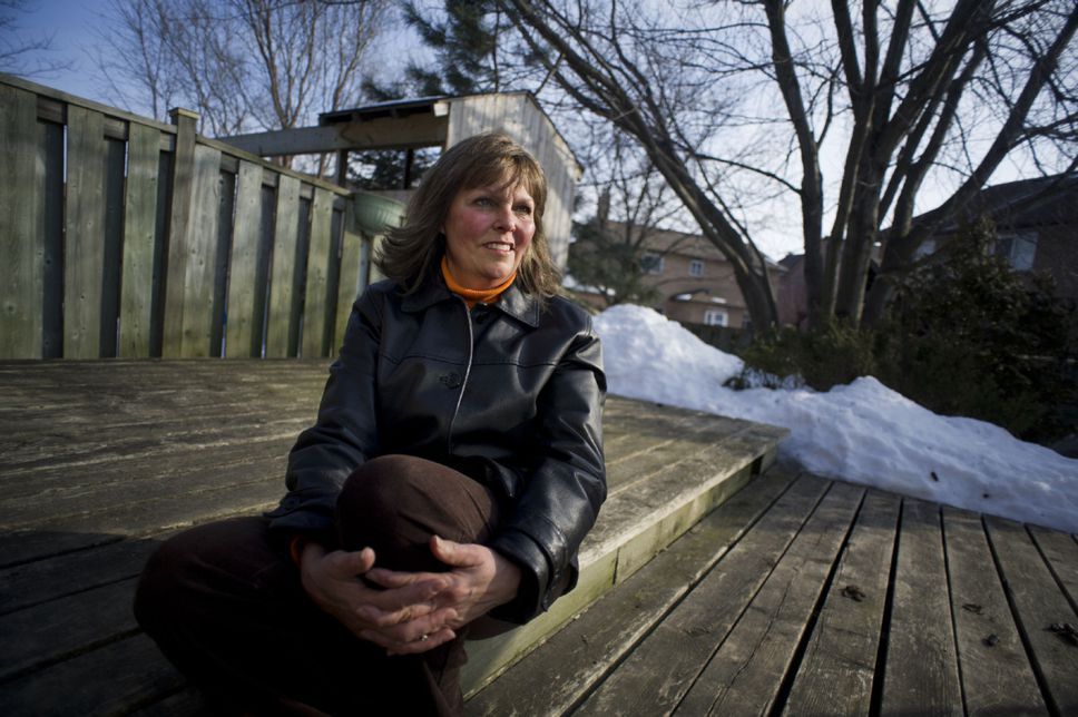 A woman in a black jacket is sitting on a wooden deck