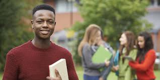 A young man is holding a book in front of a group of students.