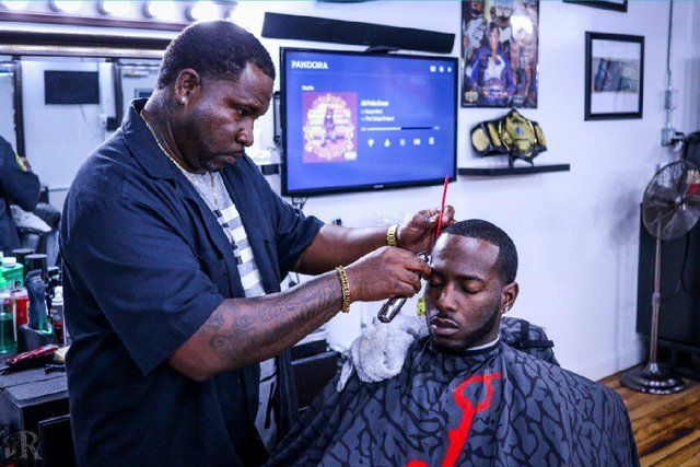 A man is getting his hair cut by a barber in a barber shop.