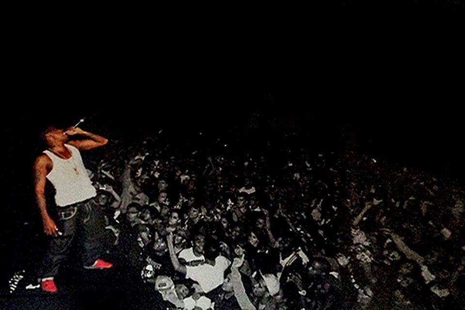 A man is standing on a stage holding a microphone in front of a crowd.