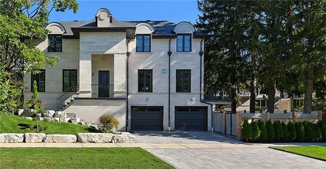 A large white house with two garages and a driveway in front of it.