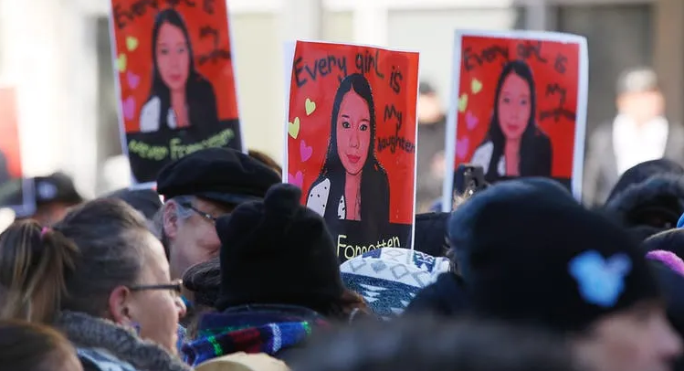 A group of people are holding signs with pictures of a woman on them.