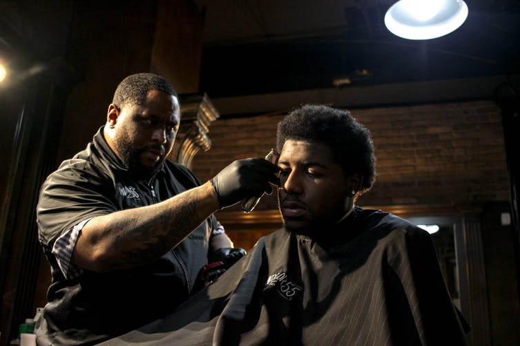 A man is getting his hair cut by a barber in a barber shop.