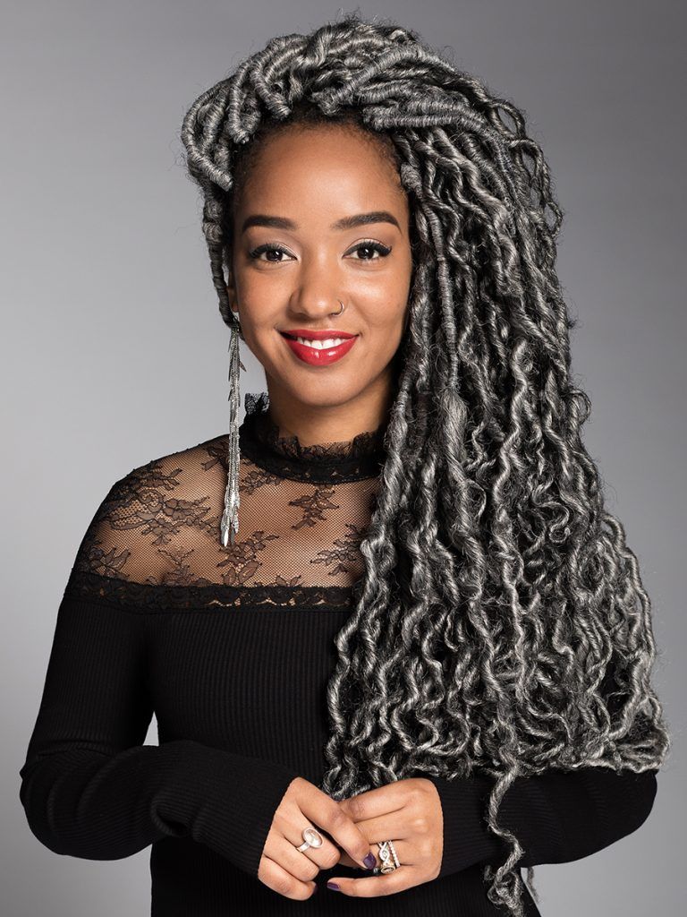 A woman with gray dreadlocks is wearing a black lace top.