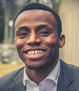 A man in a suit and white shirt is smiling for the camera.