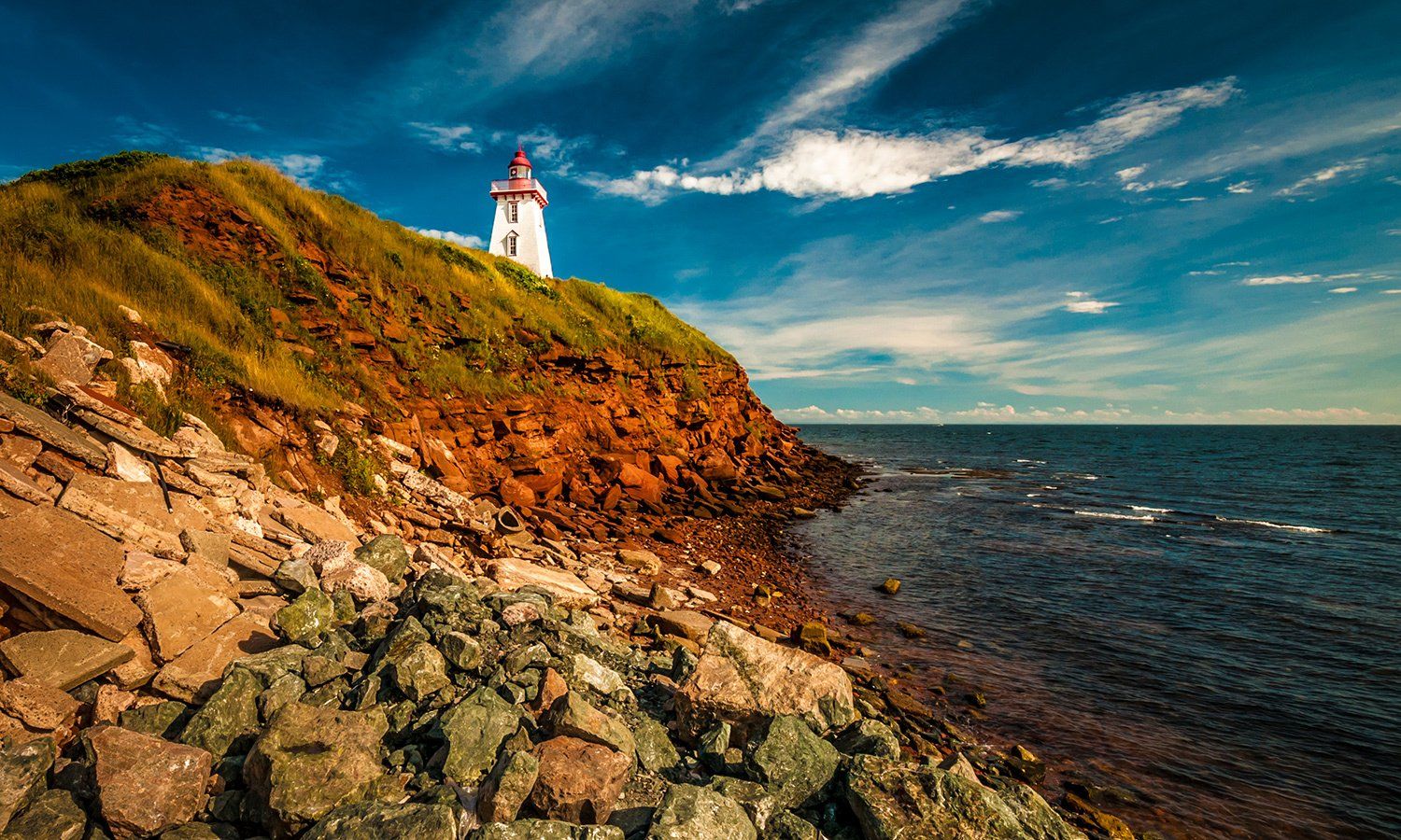 A lighthouse on top of a rocky cliff overlooking the ocean.