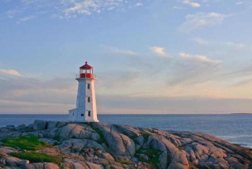 A lighthouse is sitting on top of a rocky cliff overlooking the ocean.