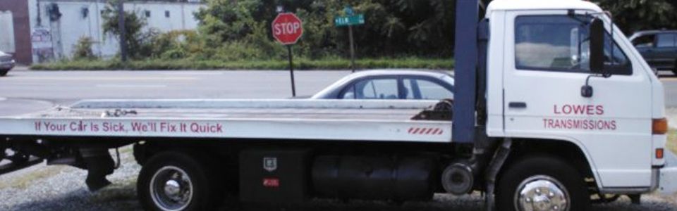 A white tow truck with a stop sign in the background