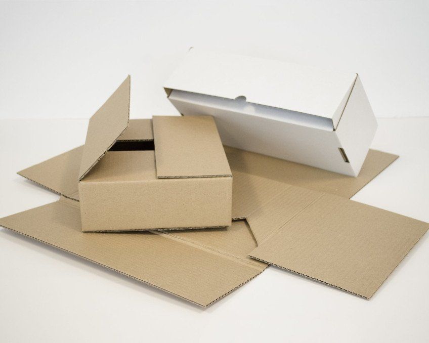 Kartonnen dozen, open en gesloten, met kartonnen vellen op een witte ondergrond.
