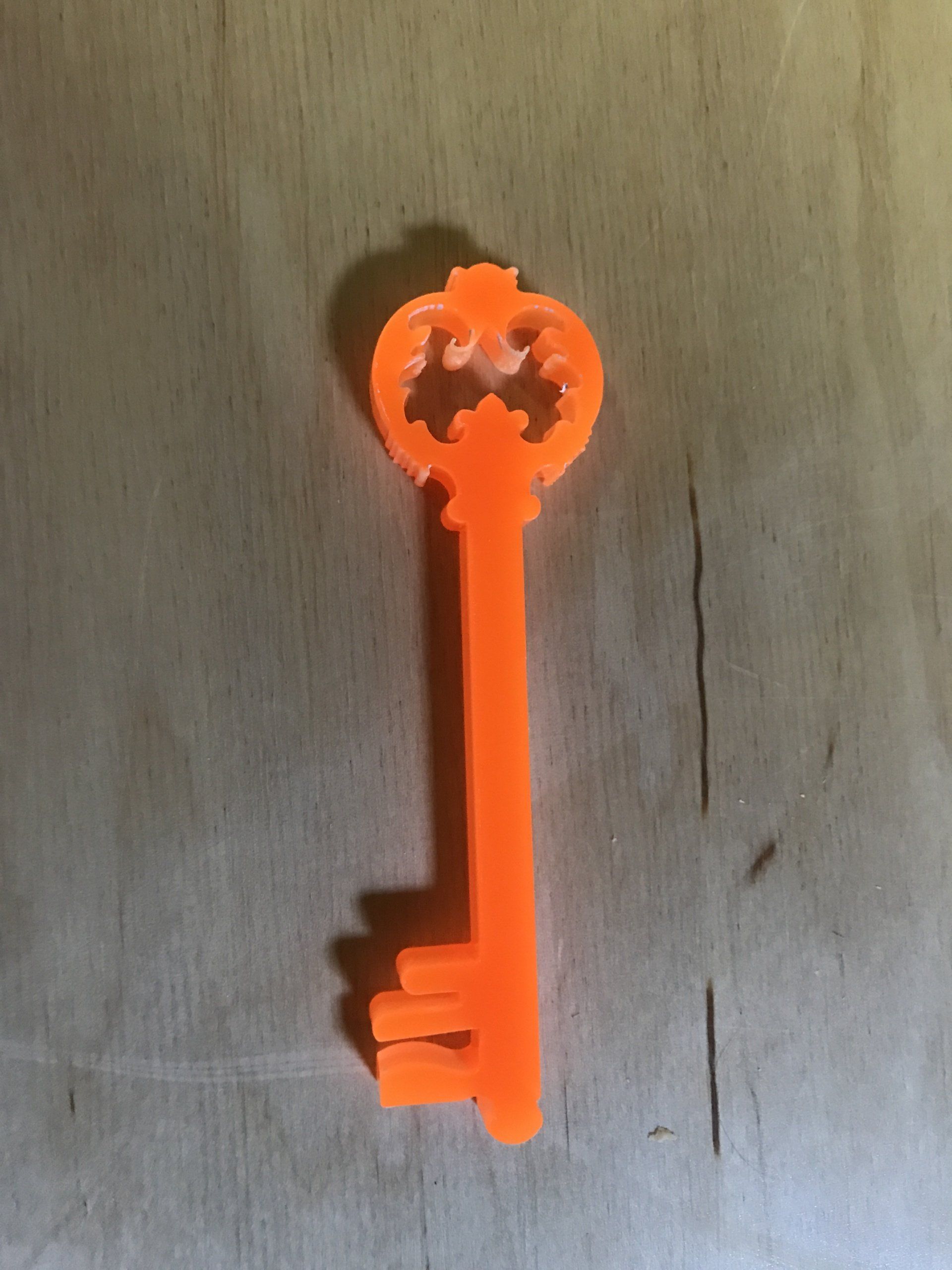 Oranje decoratieve sleutel op een licht houten oppervlak.