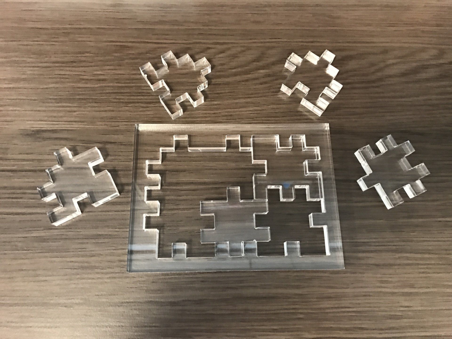 Een transparante acryl puzzel met vier stukjes die verspreid over het frame liggen.
