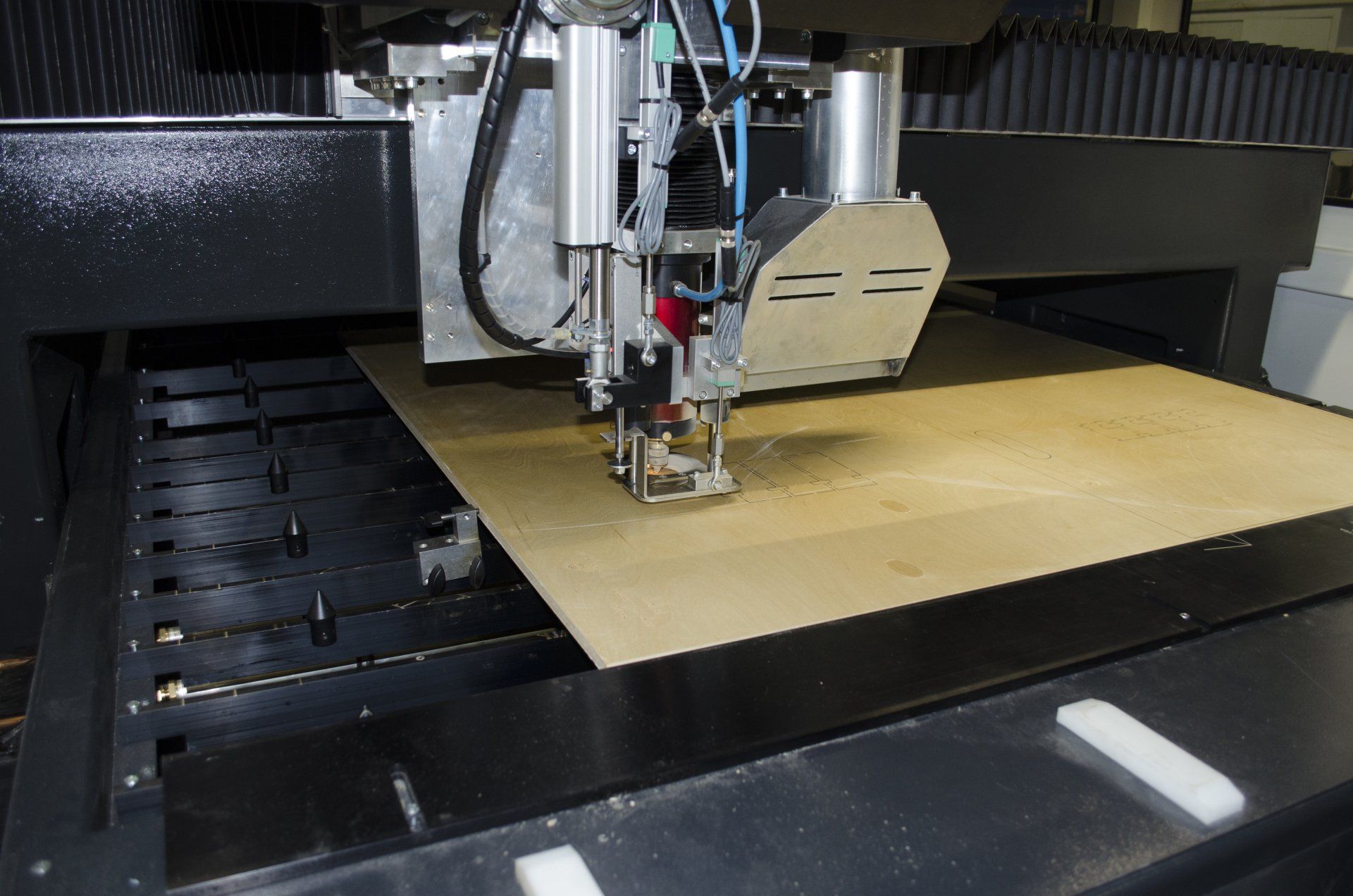CNC-machine die een grote houten plaat uitsnijdt. Close-up van de bewegende snijkop, het metalen frame en het zwarte frame.