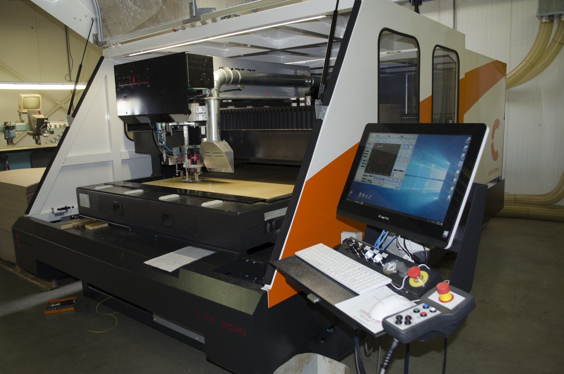 CNC-machine met computermonitor, oranje accenten en bedieningspaneel.