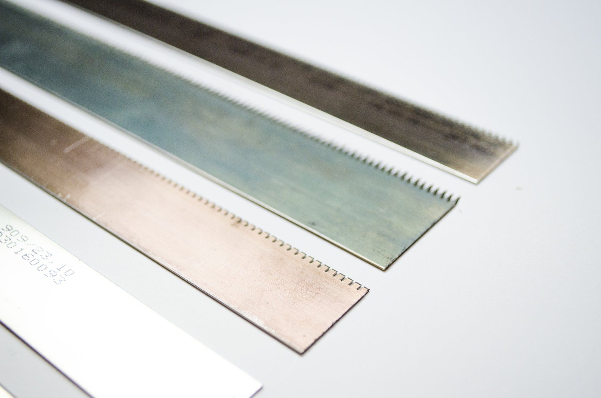 Metalen zaagbladen met gekartelde randen, in diverse kleuren en afwerkingen.