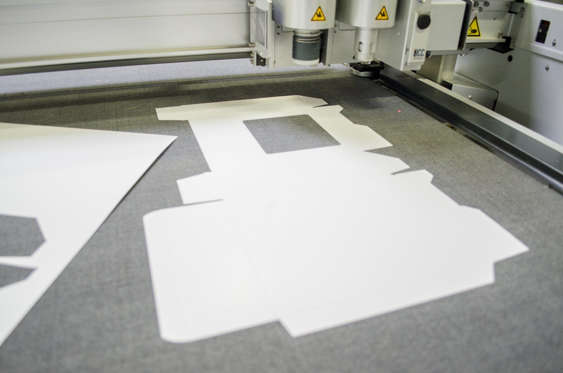 Wit karton wordt door een CNC-machine gesneden in een fabrieksomgeving.