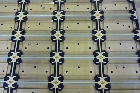 Houten oppervlak met verticale rijen zwarte en beige decoratieve elementen en kleine zwarte stippen.