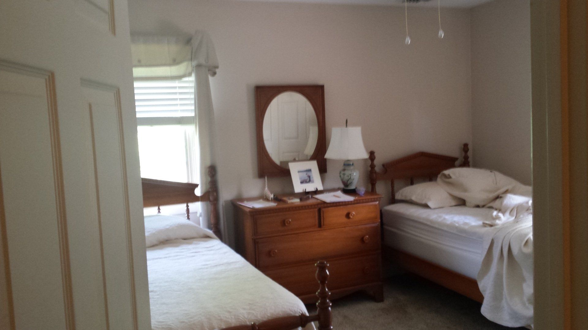 A bedroom with two beds a dresser and a mirror