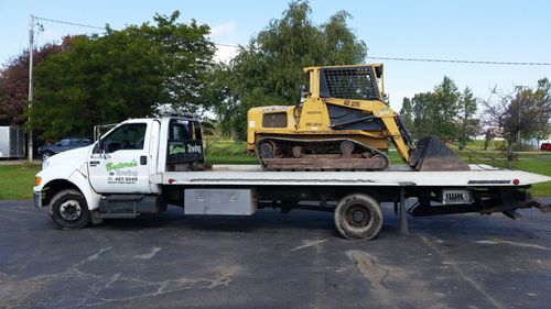 a yellow bulldozer is on the back of a tow truck