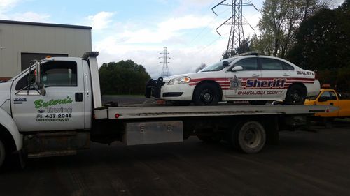 a sheriff 's car is on the back of a tow truck