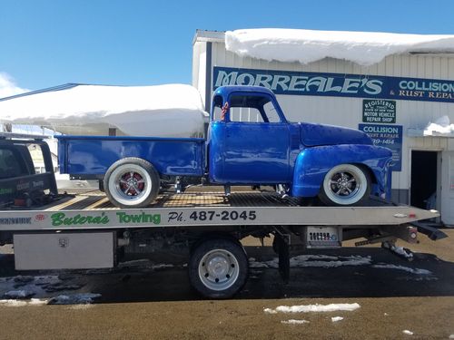 a blue truck is on the back of a towing truck