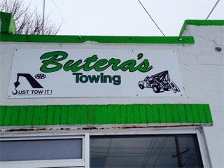 a green and white sign on the side of a building that says butera 's towing .