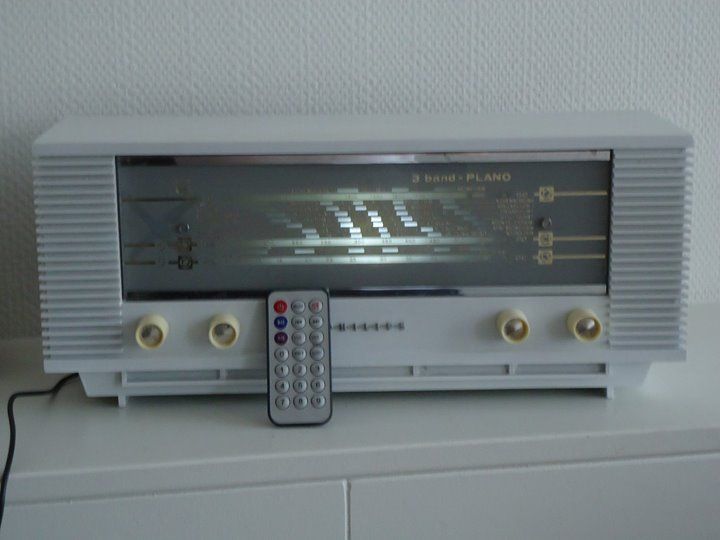 Een witte radio met daarop een afstandsbediening