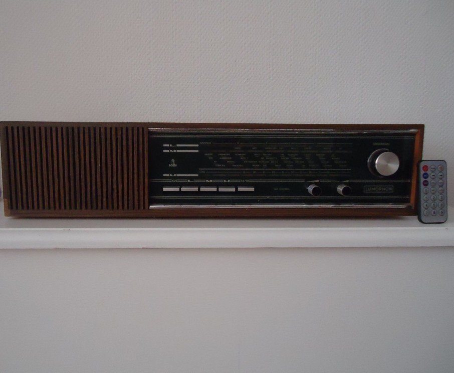 A radio is sitting on a shelf next to a remote control