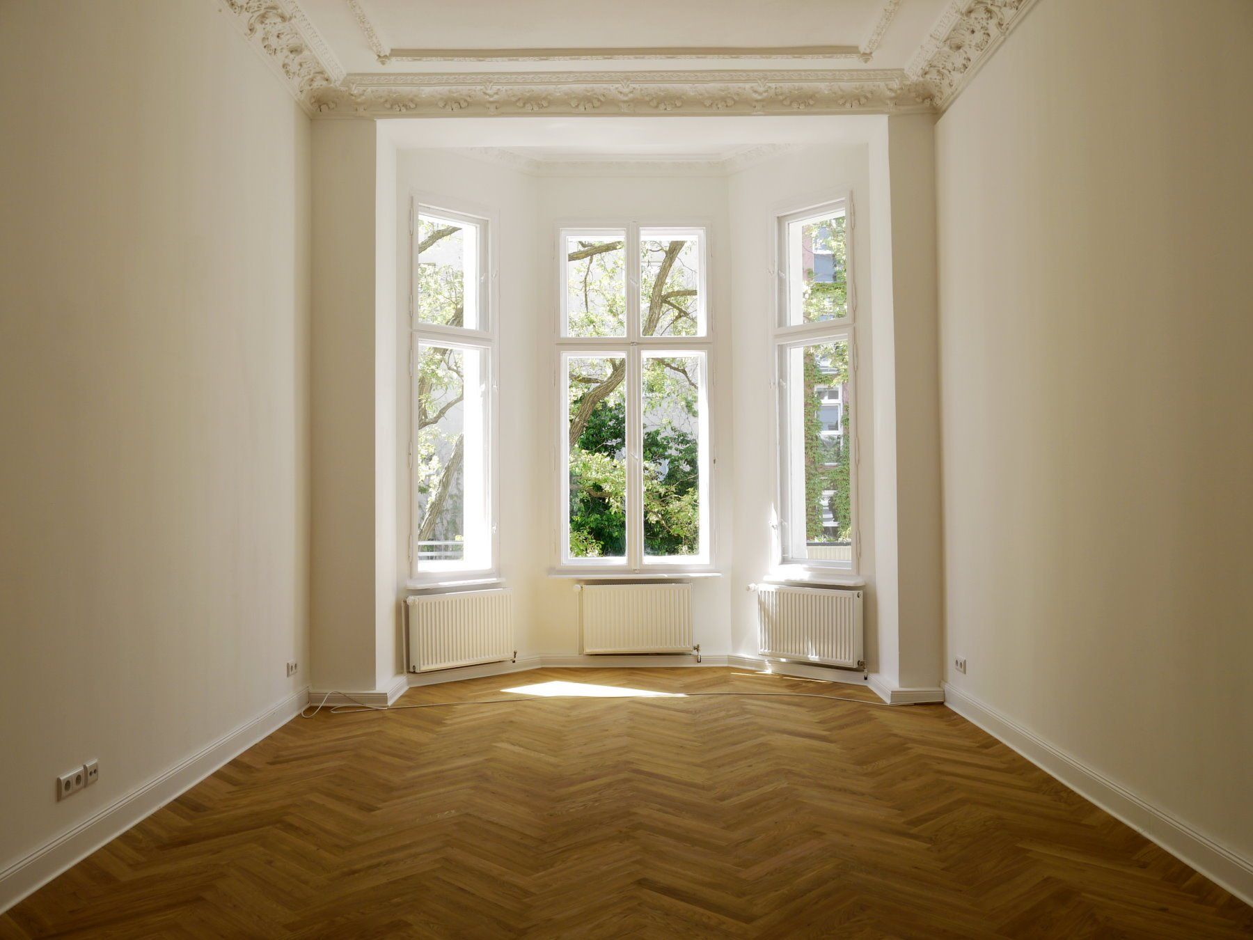 Ein leerer Raum mit einem großen Fenster und einem Holzboden.