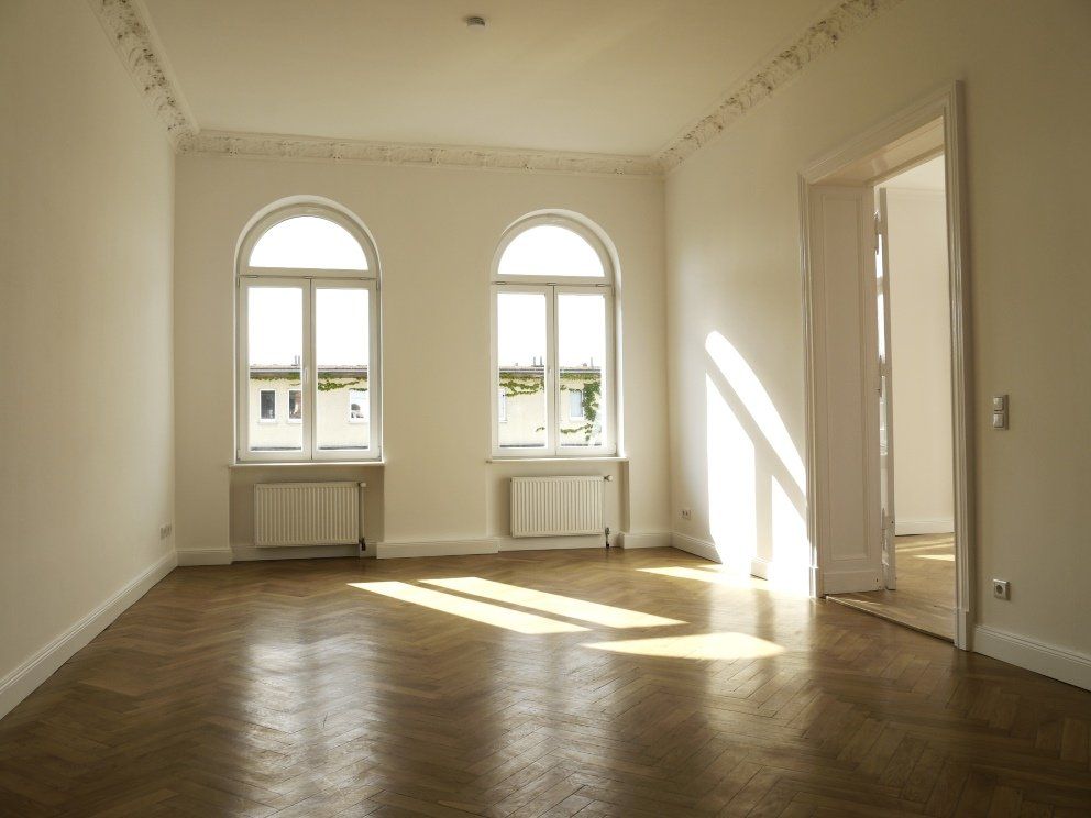 Ein leerer Raum mit Bogenfenstern und Holzboden