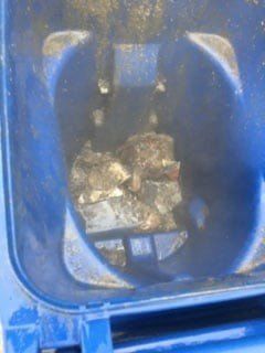 Looking down into a blue trash can, containing crumpled debris.