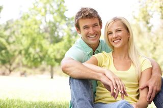 Portrait Of Young Couple Sitting In Park