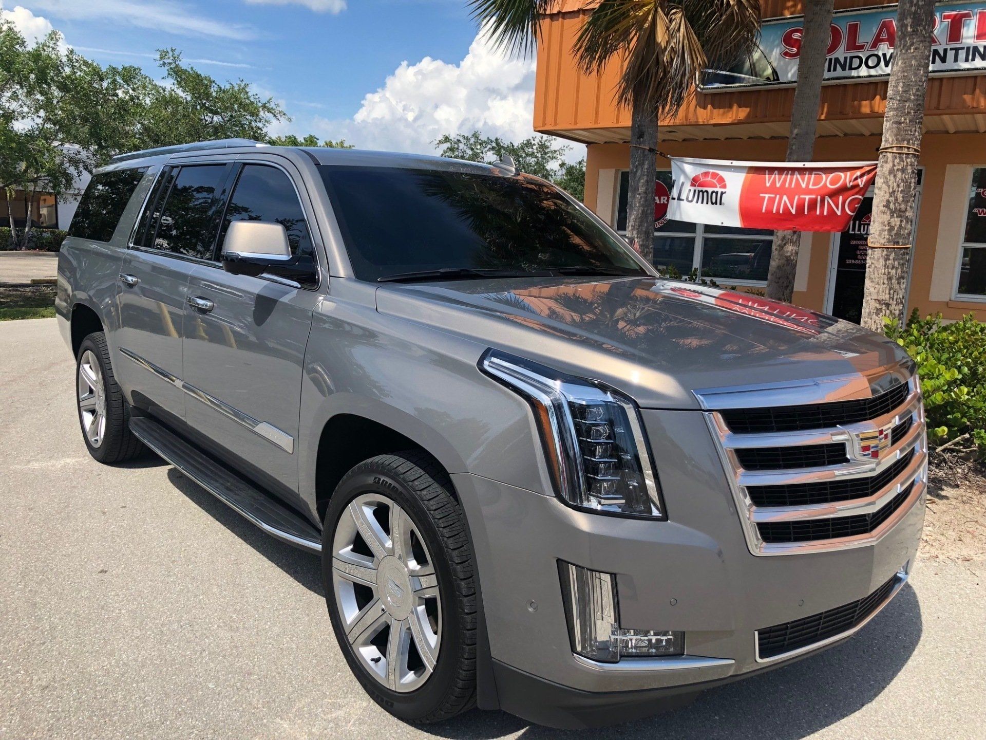 Gray Cadillac SUV with tinted windows parked outside a building.