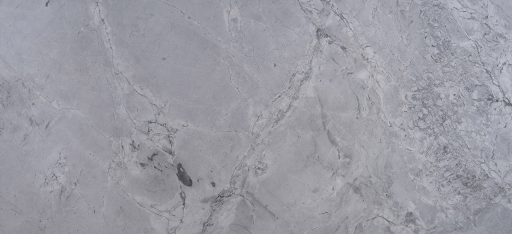 A close-up of grey marble stone featuring white, swirling veins and natural textures throughout the surface.