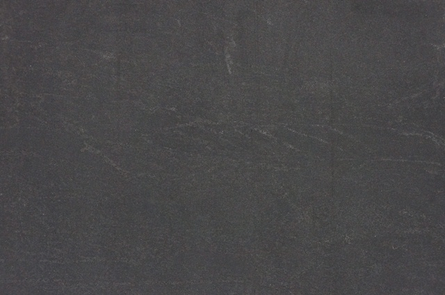 A flat, dark gray surface with a matte finish and subtle, natural stone-like texture.