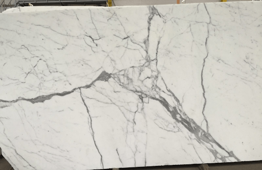 A large slab of white marble featuring prominent, jagged gray veining across its polished surface.