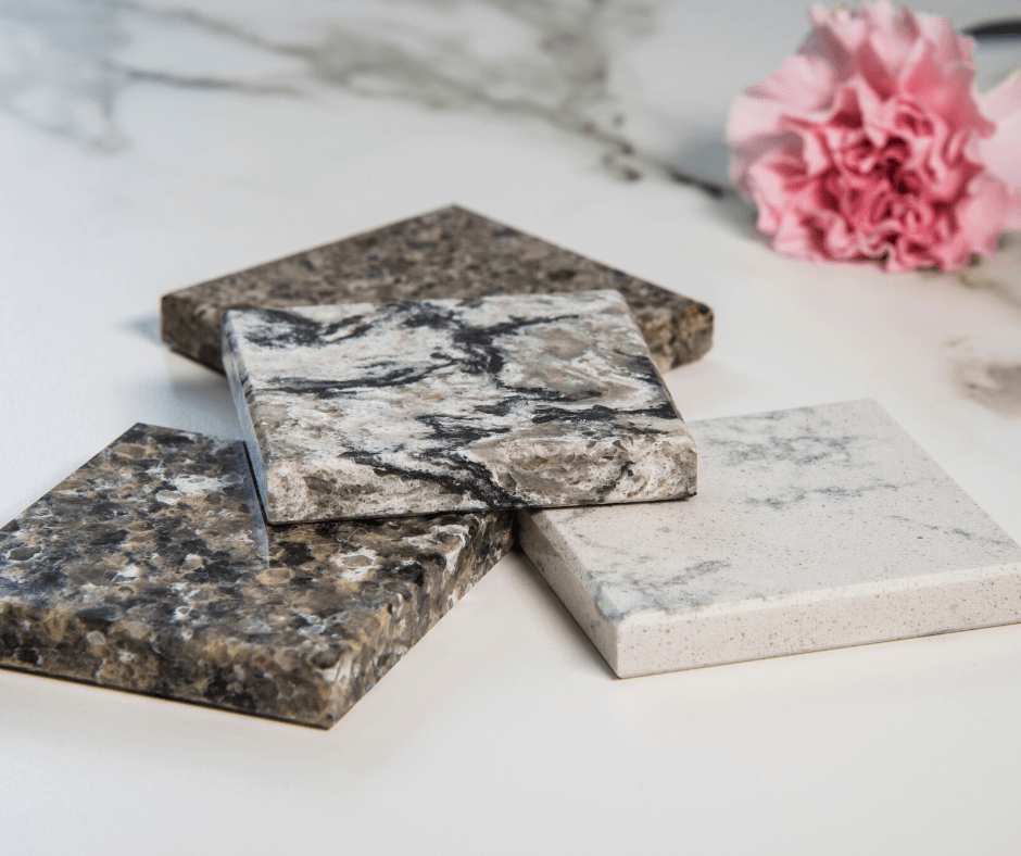 Four square countertop material samples in various stone patterns and colors, arranged on a white marble surface.