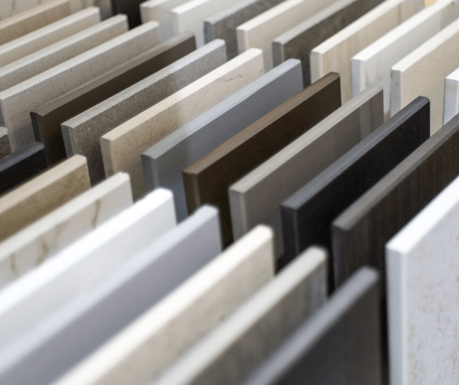 A row of various stone and tile samples standing vertically, displaying a spectrum of neutral colors and textures.