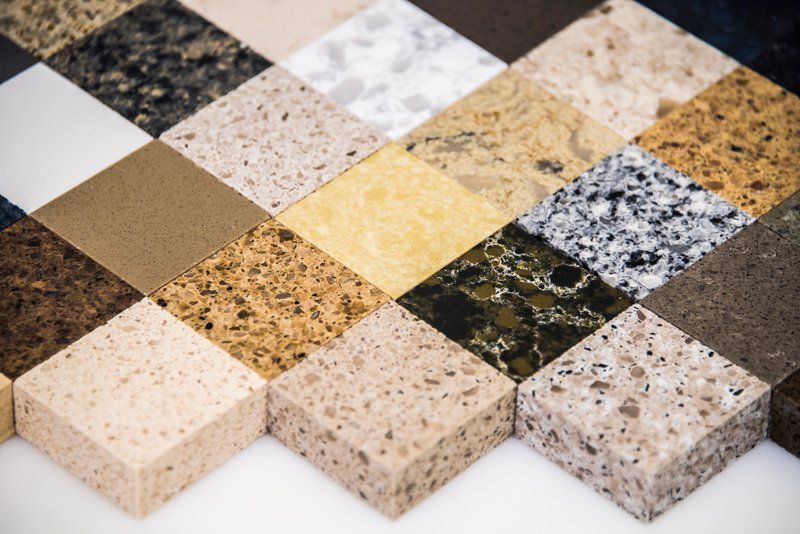 An assortment of square stone and quartz countertop samples in various colors and textures arranged in a grid.