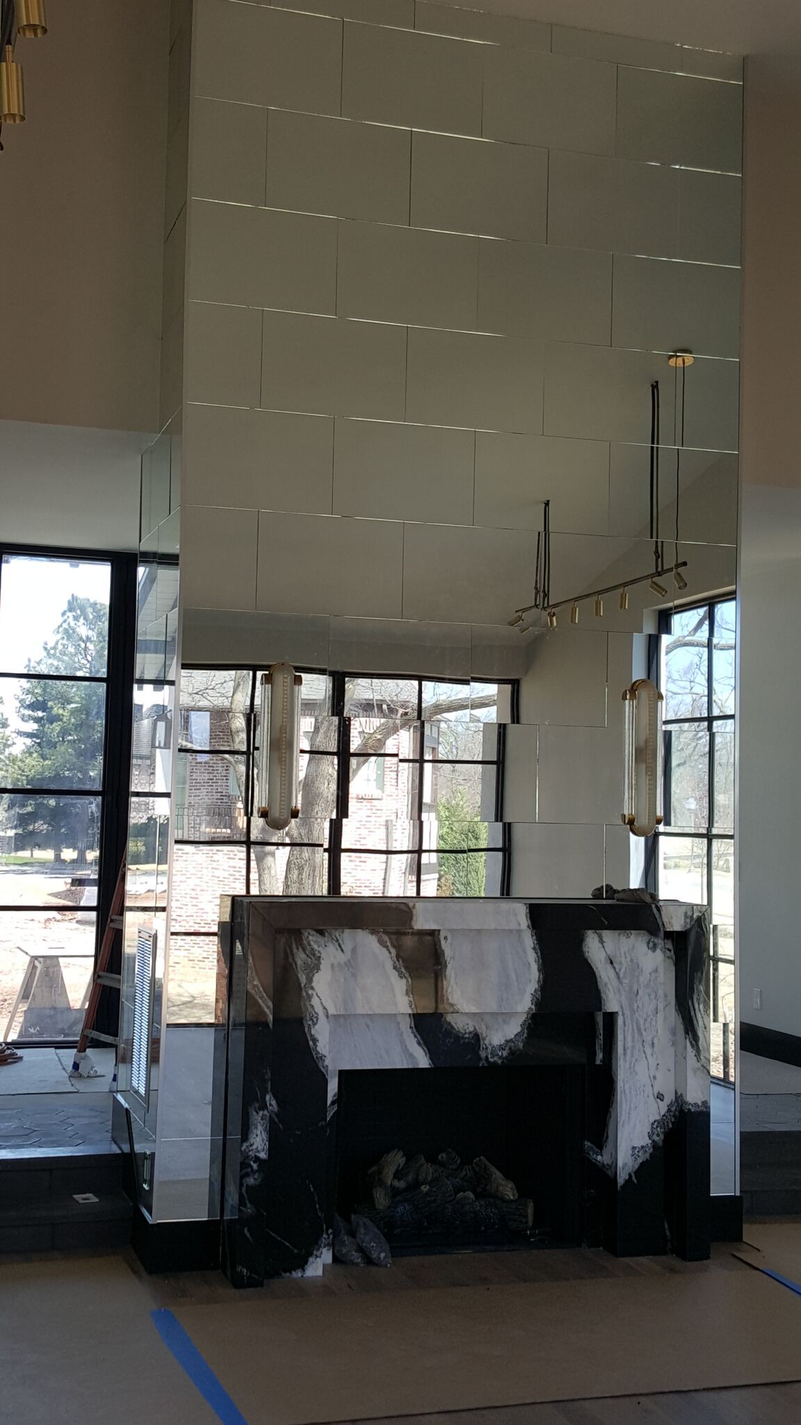 Mirrored fireplace with abstract black and white design, windows in the background.