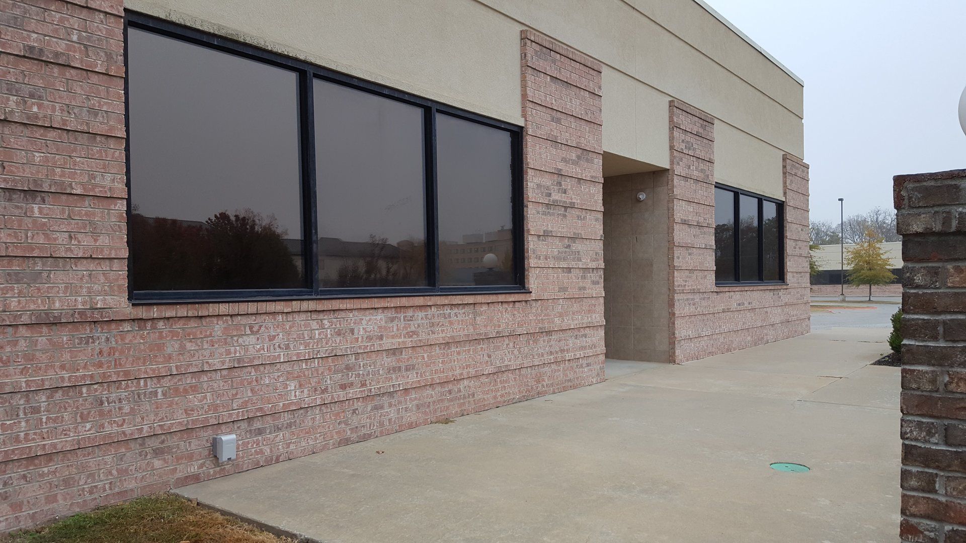Exterior view of a beige and red brick building with tinted windows and an open doorway.