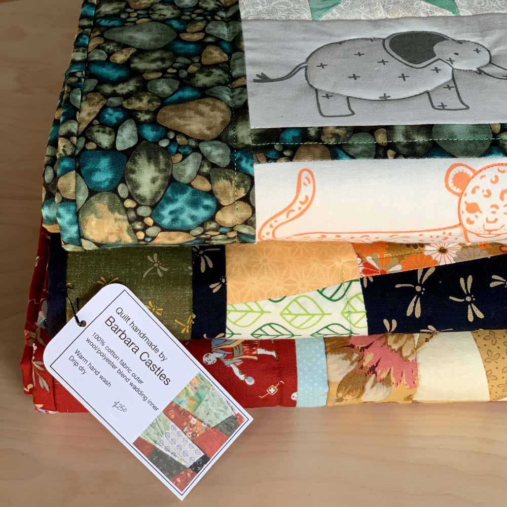 a stack of colourful quilts, made by Barbara Castles