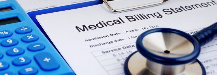 Blue calculator, medical billing statement, and stethoscope on a clipboard.