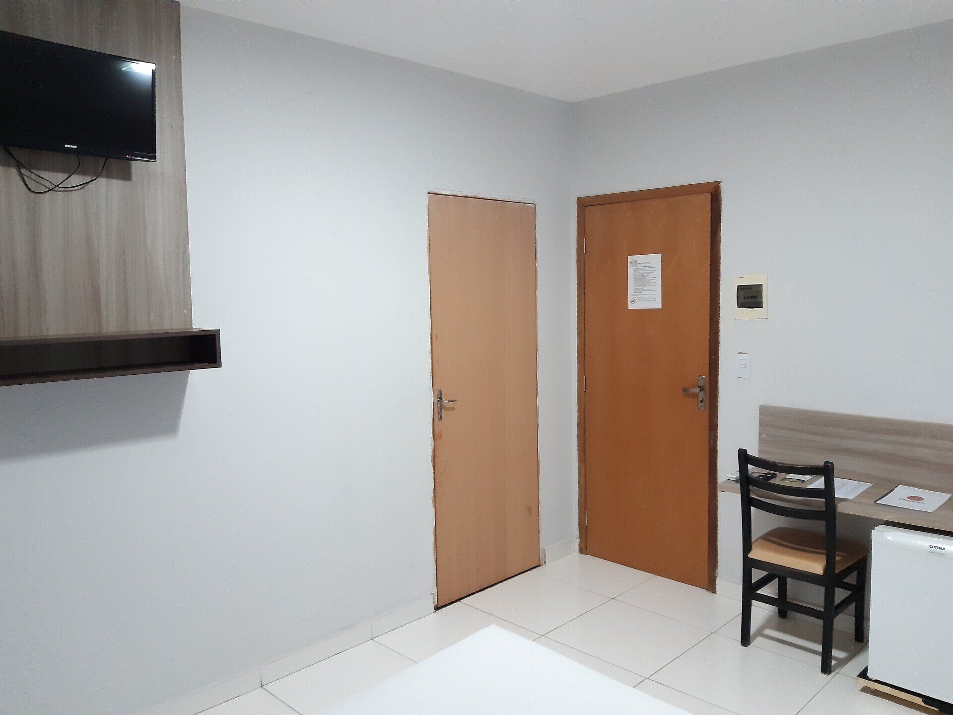 Um quarto de hotel com uma cama, escrivaninha, cadeira e televisão.
