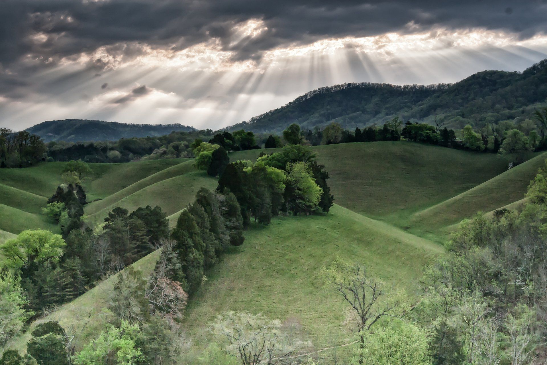 The sun is shining through the clouds over the mountains